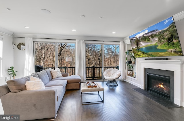 living area with a fireplace with flush hearth, ornamental molding, wood finished floors, and recessed lighting