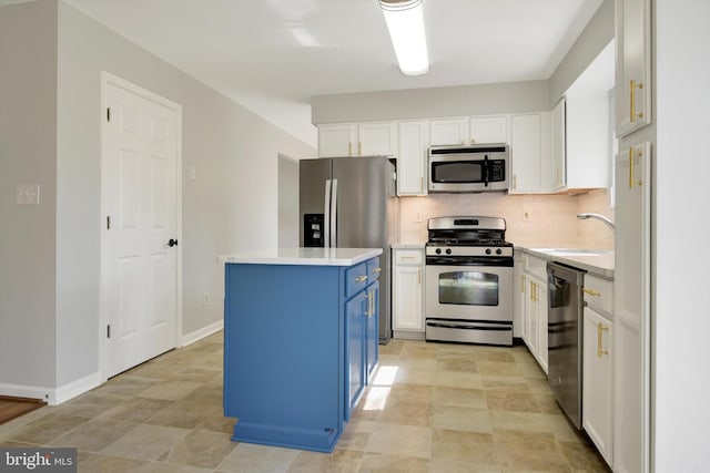 kitchen featuring stainless steel appliances, a kitchen island, a sink, blue cabinetry, and tasteful backsplash