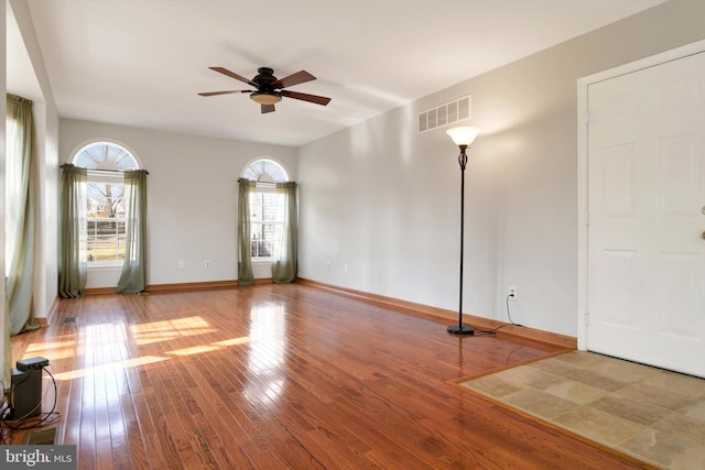 empty room featuring a wealth of natural light, wood-type flooring, and visible vents