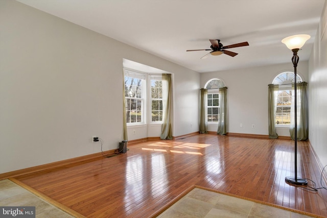 unfurnished living room featuring a ceiling fan, a wealth of natural light, baseboards, and hardwood / wood-style floors