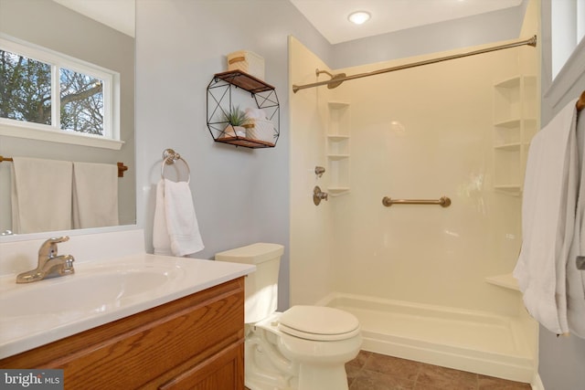 bathroom with tile patterned flooring, vanity, toilet, and walk in shower