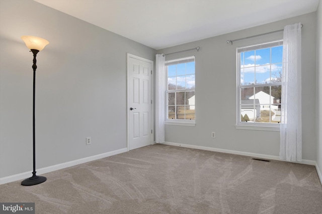 carpeted spare room with visible vents and baseboards