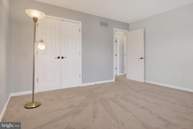 unfurnished bedroom featuring a closet, carpet, visible vents, and baseboards