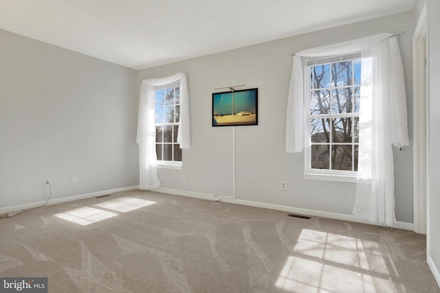 empty room with carpet, a wealth of natural light, and baseboards