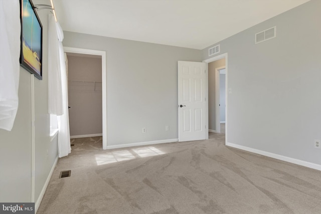 unfurnished bedroom with a spacious closet, carpet, and visible vents