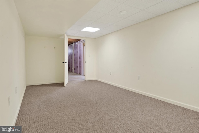 carpeted empty room with a paneled ceiling and baseboards