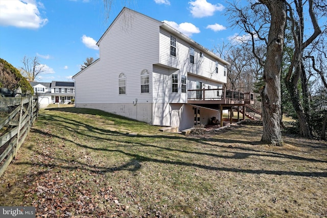 rear view of property featuring a deck, stairway, fence, and a lawn