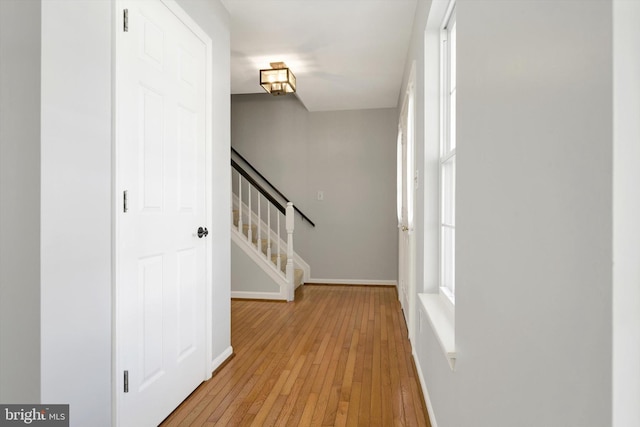 hall with stairs, light wood-style flooring, and baseboards