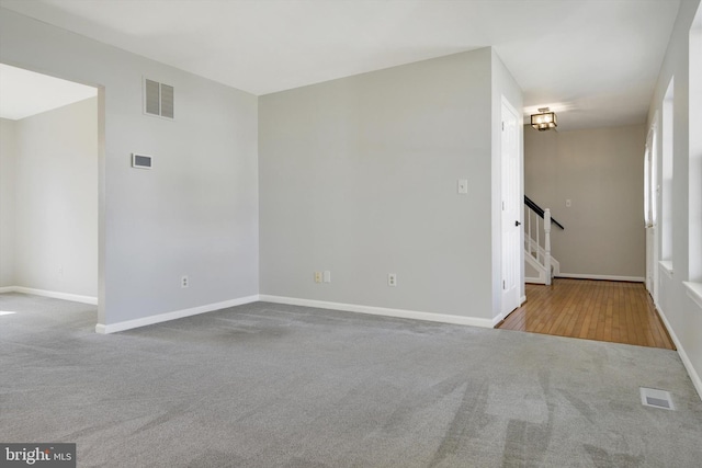 spare room with stairs, carpet, visible vents, and baseboards