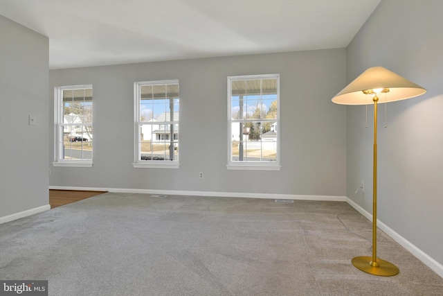 empty room with baseboards, carpet floors, and a healthy amount of sunlight