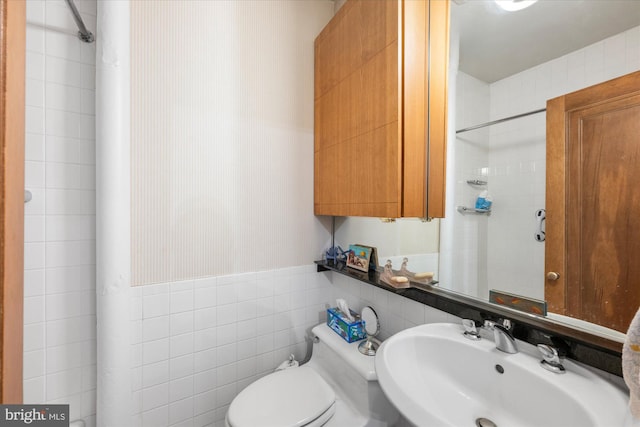 bathroom featuring toilet, tile walls, walk in shower, and a sink