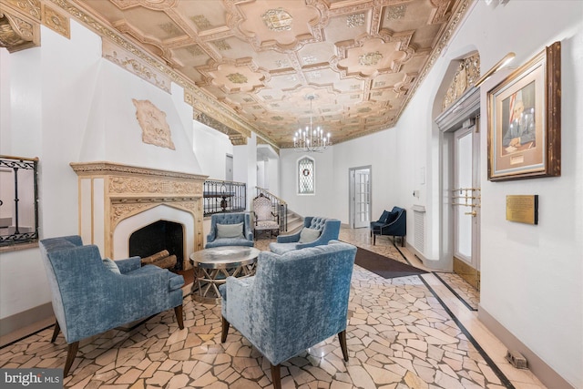 sitting room with a chandelier, a fireplace, baseboards, ornamental molding, and an ornate ceiling