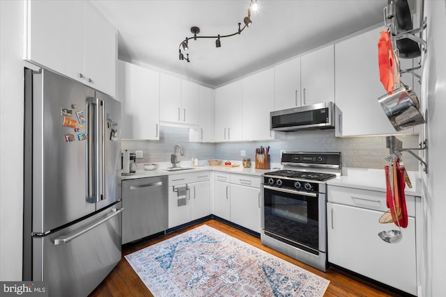 kitchen with appliances with stainless steel finishes, light countertops, a sink, and tasteful backsplash