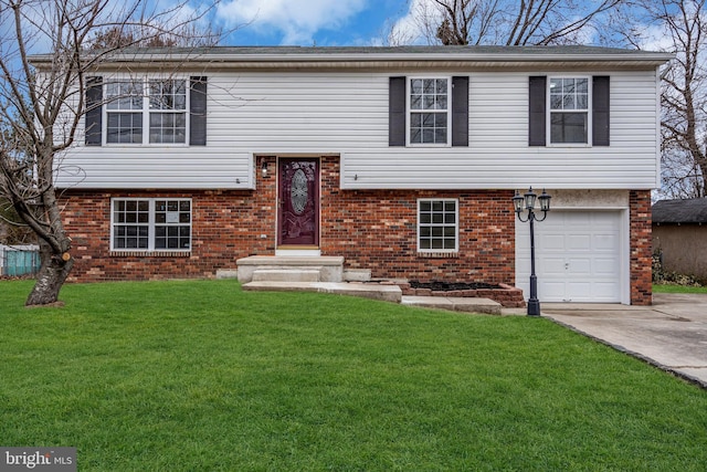 split foyer home featuring a garage, driveway, brick siding, and a front lawn