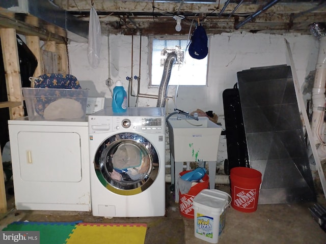 clothes washing area with laundry area, a sink, and washing machine and clothes dryer