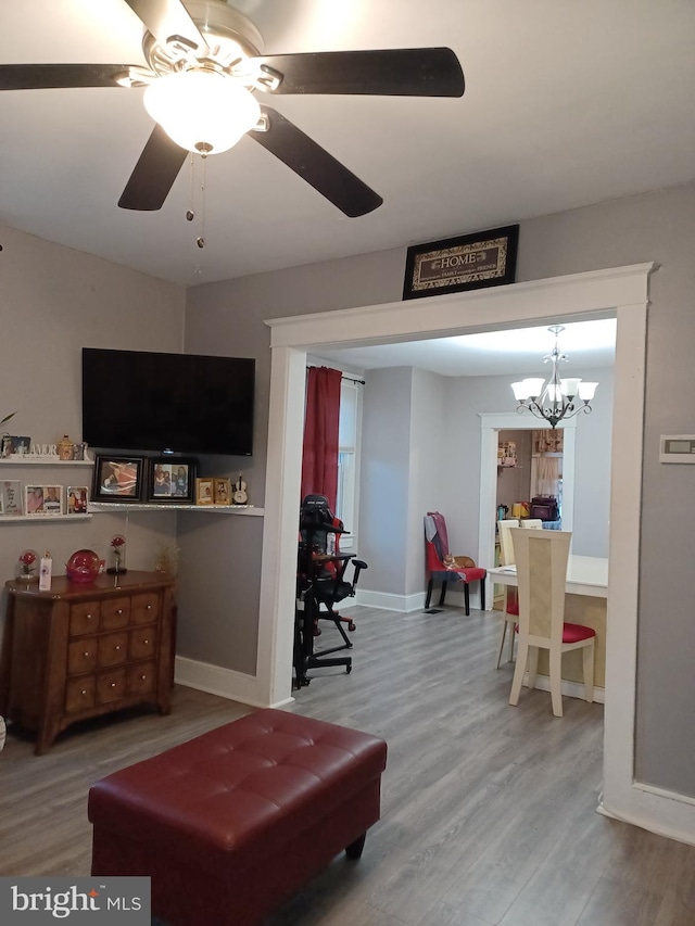 living area featuring ceiling fan, baseboards, and wood finished floors