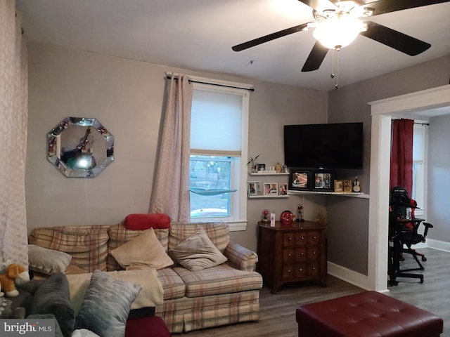 living area featuring a ceiling fan, baseboards, and wood finished floors