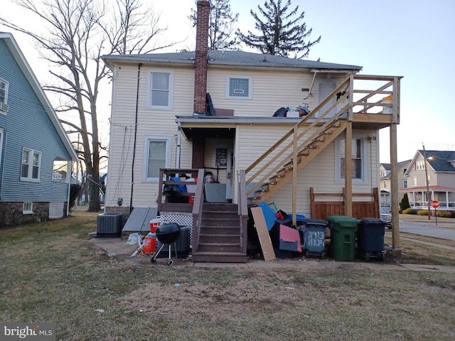 rear view of house featuring central AC, a lawn, and stairway