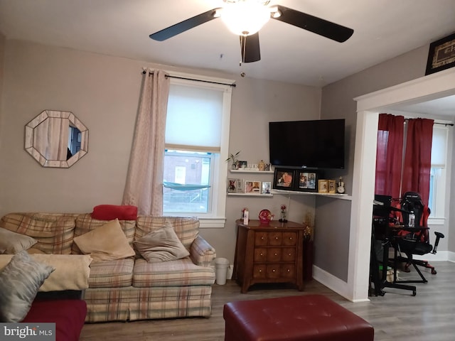 living area featuring wood finished floors, a ceiling fan, and baseboards