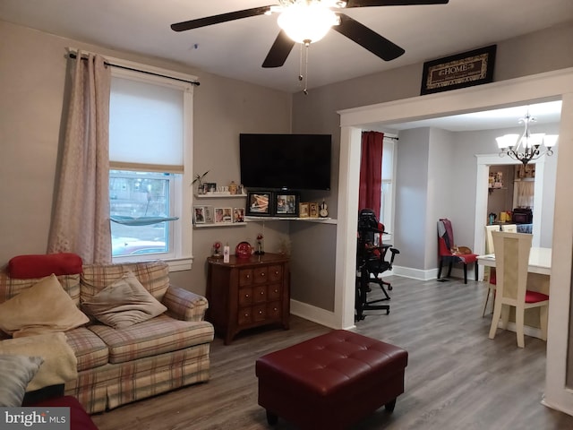 living room featuring baseboards, wood finished floors, and ceiling fan with notable chandelier