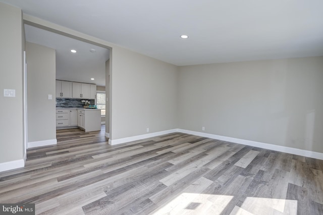 unfurnished living room featuring recessed lighting, light wood-type flooring, and baseboards