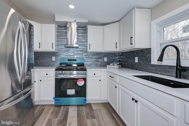 kitchen with a sink, wood finished floors, stainless steel appliances, wall chimney exhaust hood, and decorative backsplash