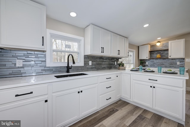 kitchen featuring light wood finished floors, open shelves, light countertops, and a sink