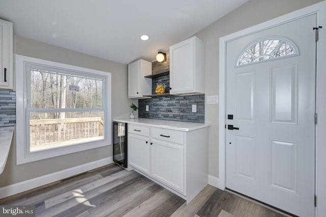 kitchen with wood finished floors, baseboards, open shelves, light countertops, and white cabinetry