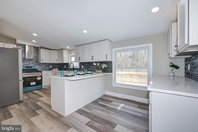 kitchen with a peninsula, light wood-style flooring, a sink, stainless steel appliances, and light countertops