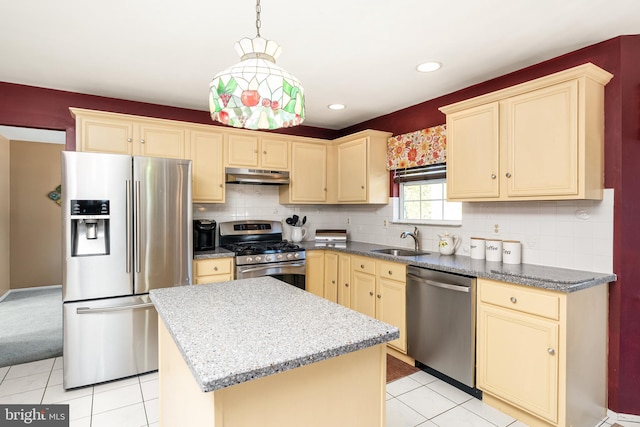 kitchen featuring stainless steel appliances, cream cabinets, light tile patterned flooring, a sink, and under cabinet range hood