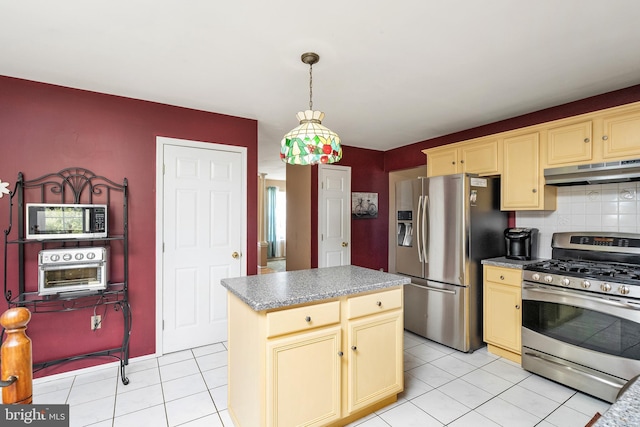 kitchen with light tile patterned floors, decorative backsplash, appliances with stainless steel finishes, a center island, and under cabinet range hood