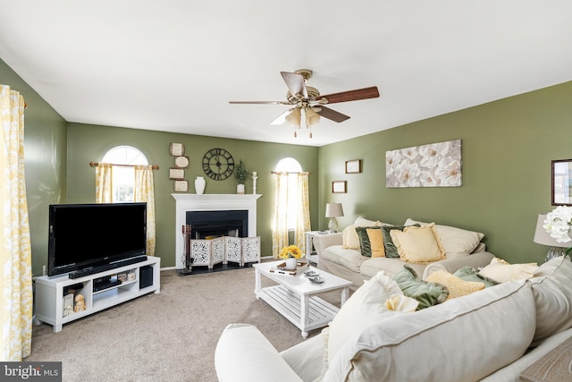 carpeted living room with ceiling fan and a fireplace