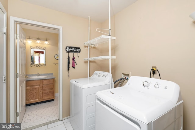 clothes washing area with laundry area, a sink, washer and clothes dryer, and light tile patterned floors