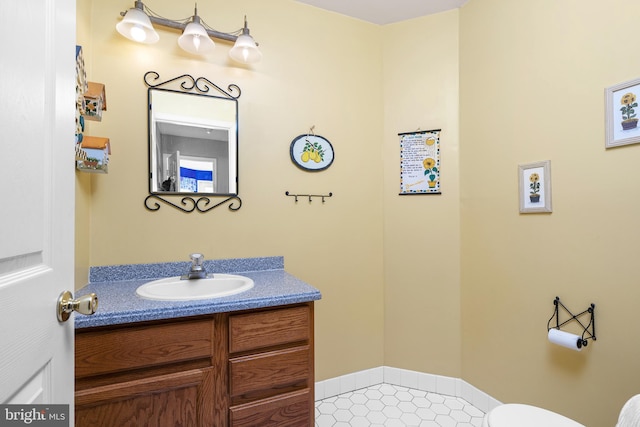 half bath with toilet, tile patterned floors, and vanity