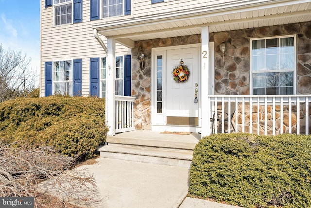 doorway to property featuring stone siding and covered porch