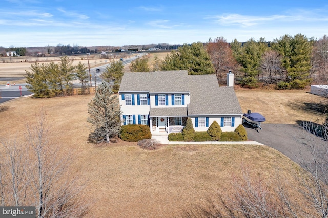 view of front of house featuring a porch, a front yard, driveway, and a chimney