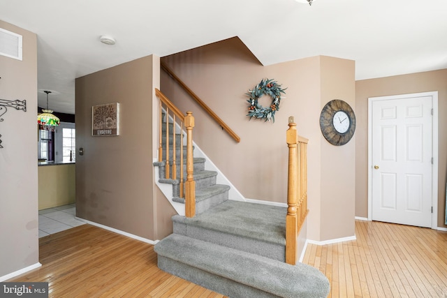 staircase featuring wood-type flooring, visible vents, and baseboards