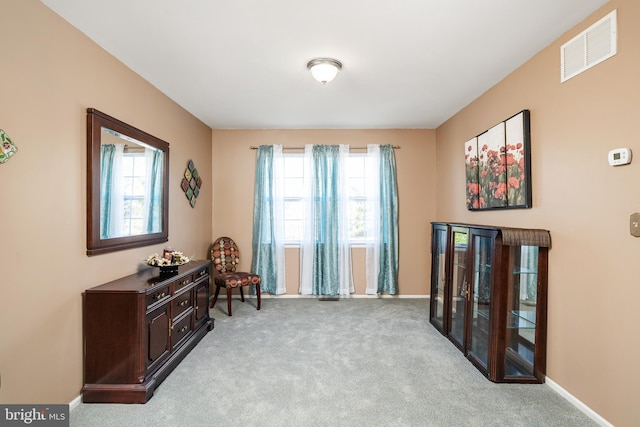 living area with carpet, plenty of natural light, visible vents, and baseboards