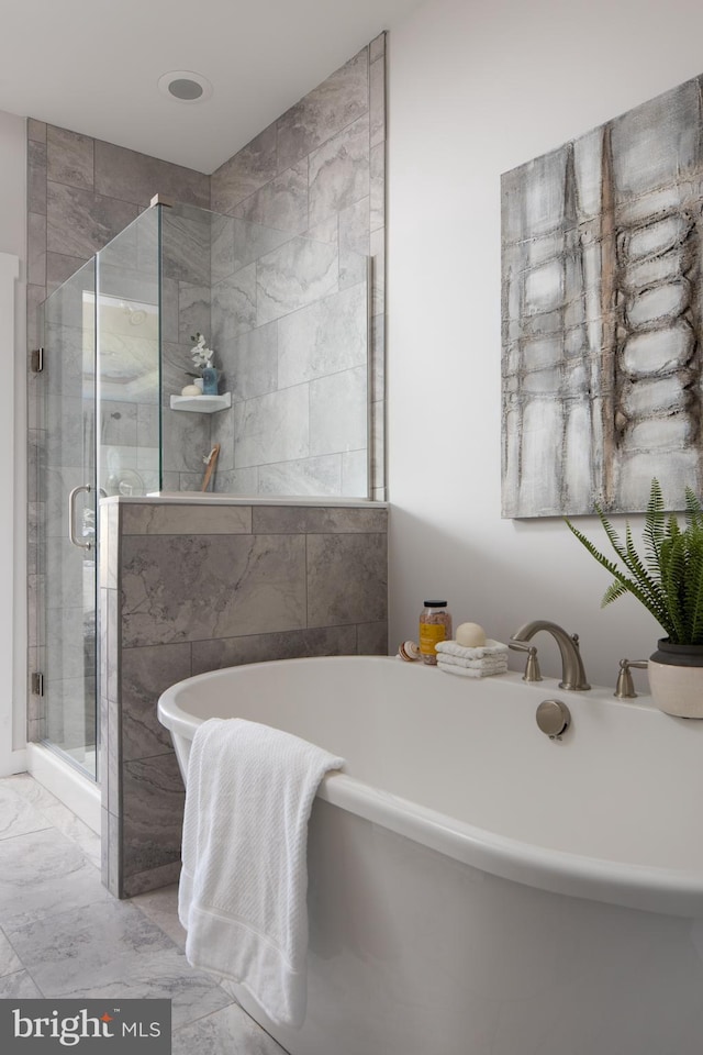 full bathroom with marble finish floor, a freestanding tub, and a shower stall