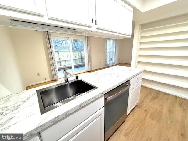 kitchen featuring white cabinets, a sink, light stone countertops, light wood-type flooring, and dishwasher