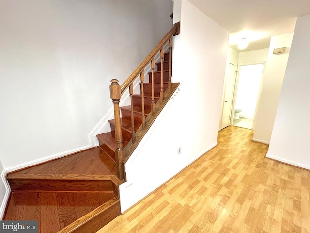 staircase featuring baseboards and wood finished floors