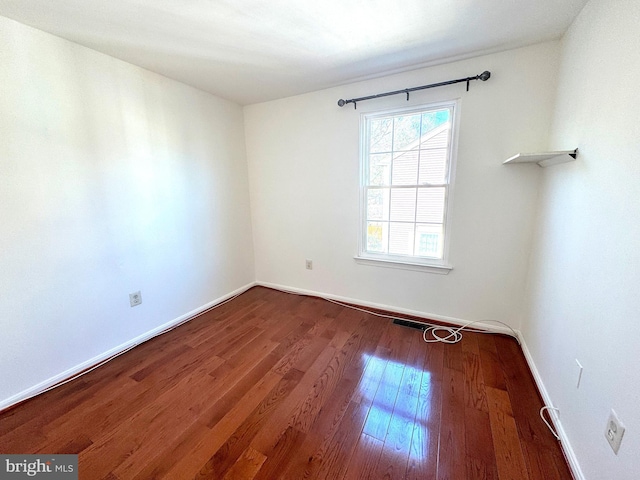 spare room with baseboards, visible vents, and hardwood / wood-style floors