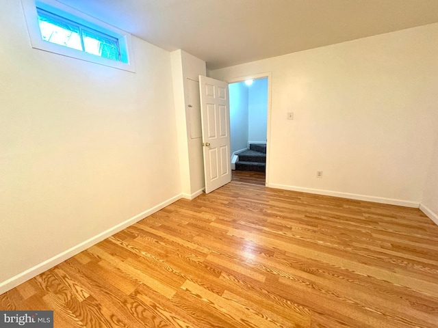 spare room featuring baseboards, stairway, and light wood-style floors