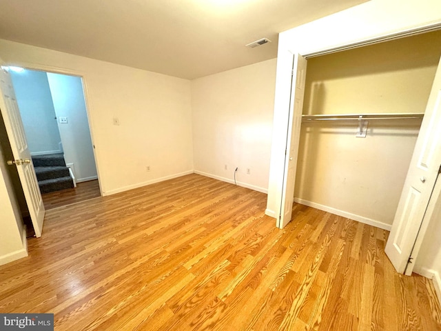 unfurnished bedroom with light wood-type flooring, baseboards, visible vents, and a closet