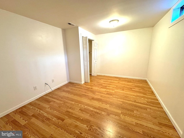 unfurnished room featuring visible vents, light wood-style flooring, and baseboards