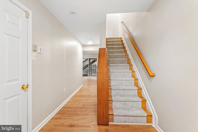 staircase with baseboards and wood finished floors