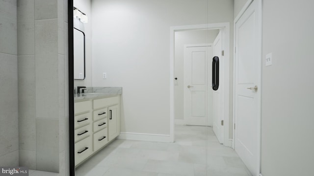 full bath featuring a closet, vanity, and baseboards