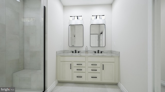 bathroom featuring a stall shower, a sink, baseboards, and double vanity