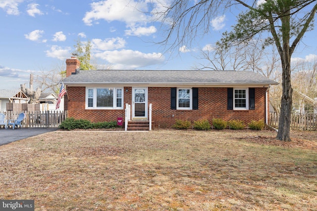 ranch-style home with entry steps, a chimney, fence, and brick siding