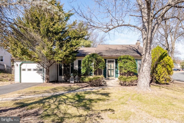 view of front facade featuring aphalt driveway, a front yard, a chimney, and a garage